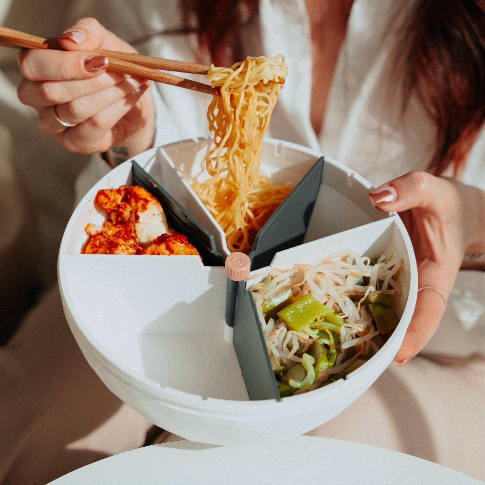 Bol maju de couleur blanc rempli avec des pâtes mangées avec des baguettes chinoises.