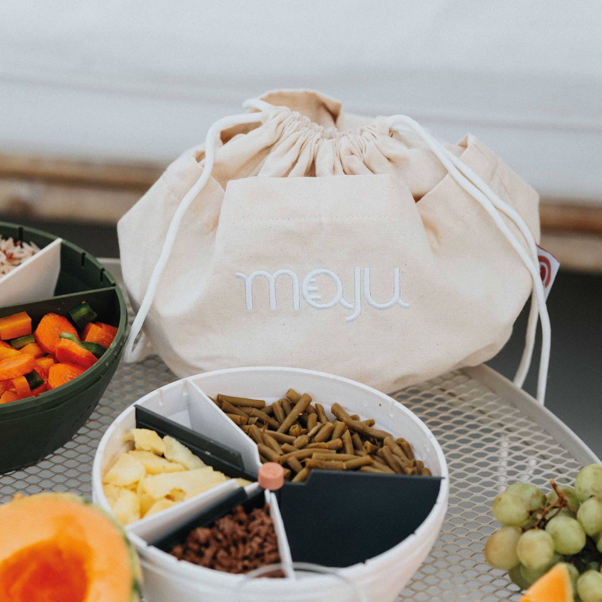 Sac de transport maju en coton et de couleur crème posé sur une table avec un bol maju de couleur blanc devant. 