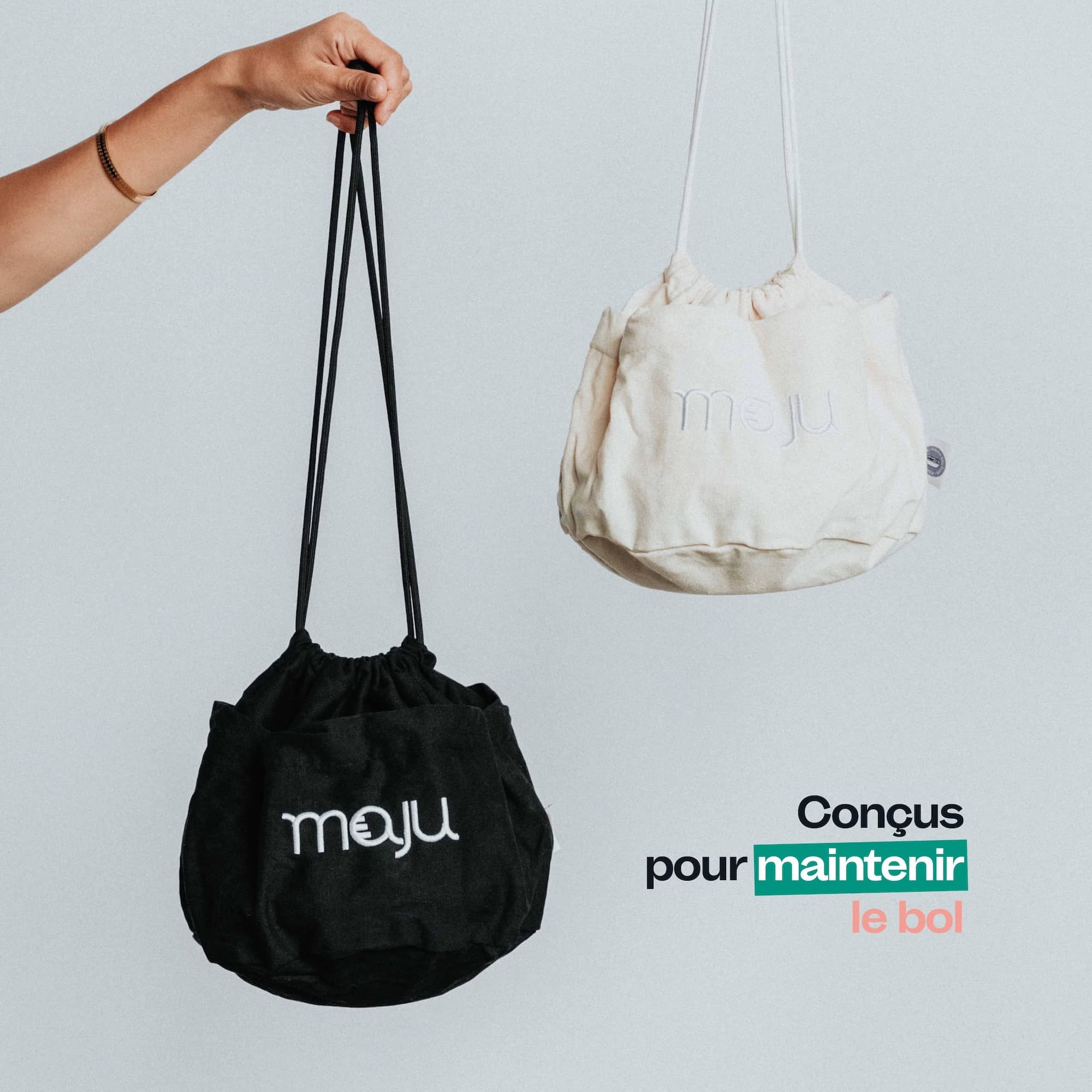 2 sac de transport en coton maju de couleur crème et noir, maintenus par la main.