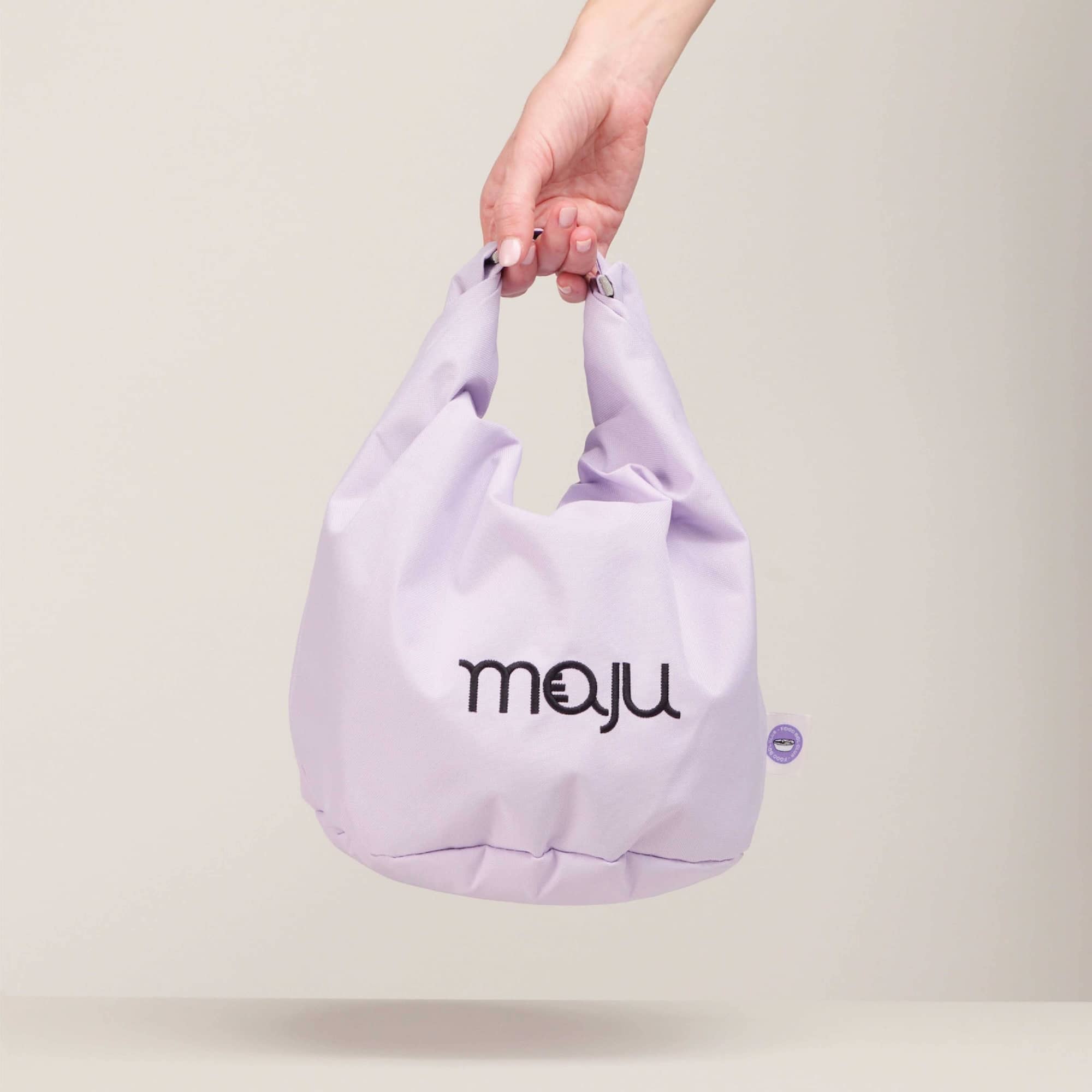 Sac isotherme maju de couleur violet maintenu par la main. 